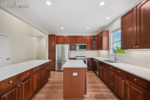 a large kitchen with stainless steel appliances wooden cabinets a center island and a refrigerator