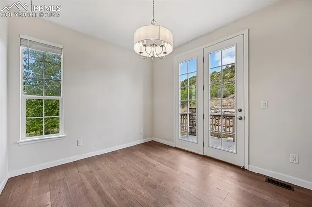 an empty room with wooden floor fan mirror and windows