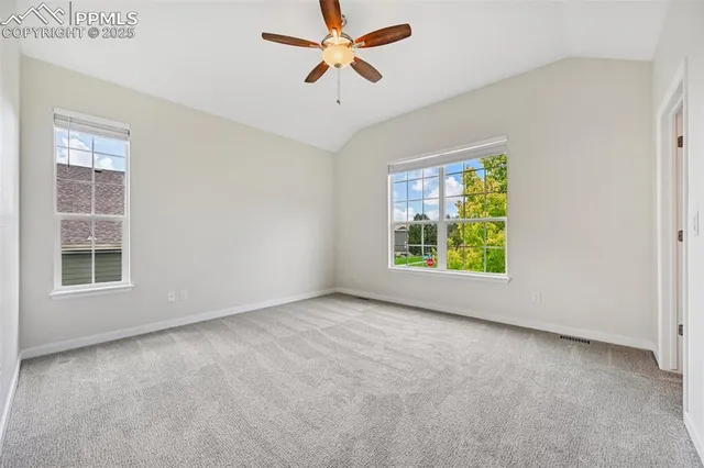 an empty room with windows and chandelier fan