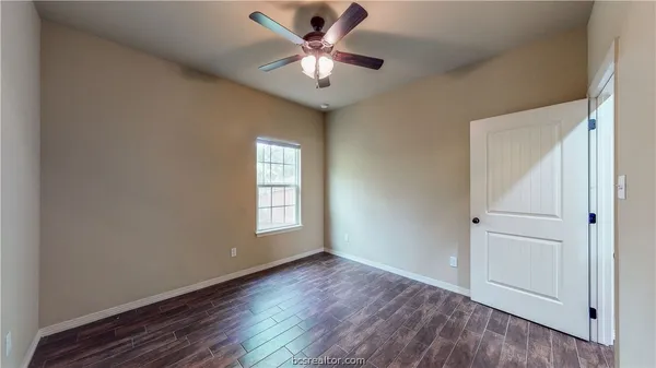 an empty room with wooden floor and ceiling fan