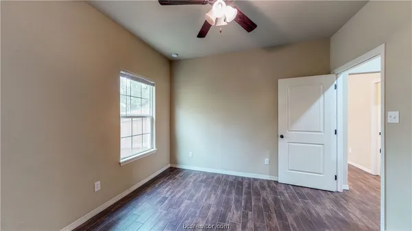 an empty room with wooden floor cabinet and windows
