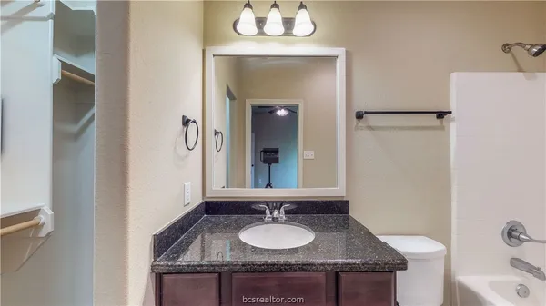a bathroom with a granite countertop sink and a mirror
