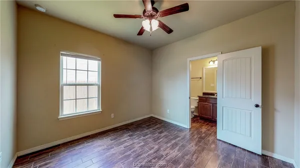 a view of empty room with wooden floor and fan