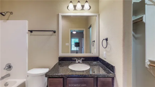 a bathroom with a granite countertop sink toilet and mirror
