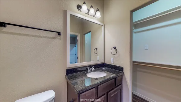a bathroom with a granite countertop sink and a mirror