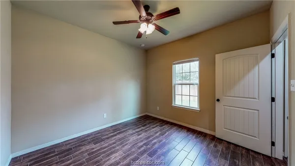 an empty room with wooden floor chandelier fan and windows