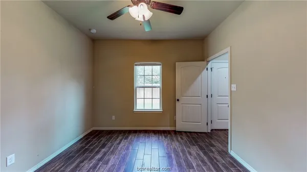 an empty room with wooden floor chandelier fan and windows