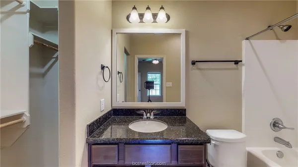 a bathroom with a granite countertop sink and a mirror