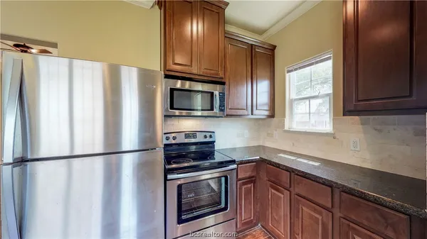 a kitchen with granite countertop a refrigerator stove and microwave