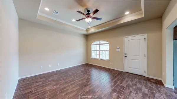 wooden floor in an empty room with a ceiling fan and window