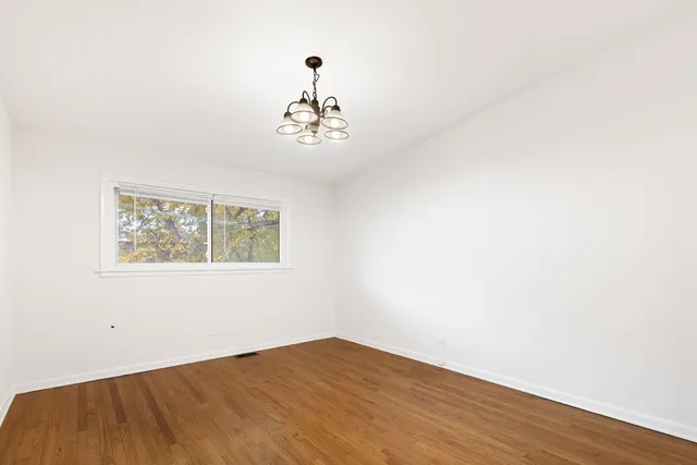 an empty room with wooden floor and chandelier fan