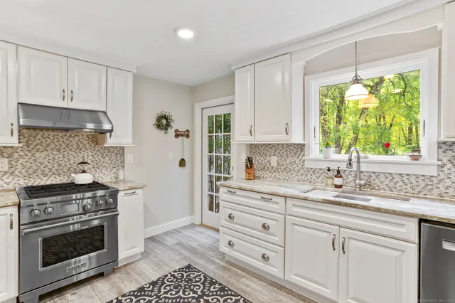 a kitchen with stainless steel appliances white cabinets and a stove top oven