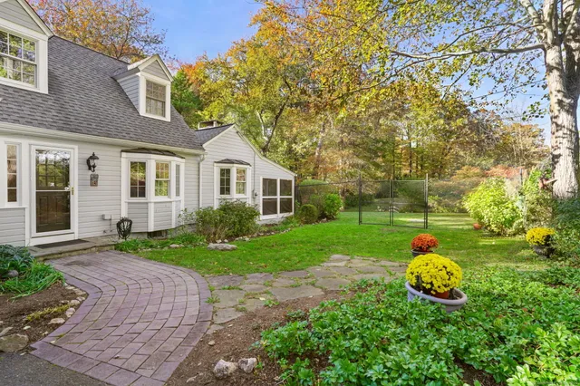 a backyard of a house with table and chairs plants and large tree