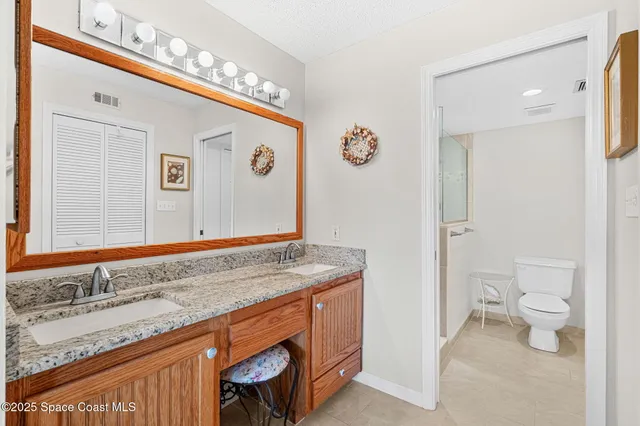 a bathroom with a granite countertop sink and a toilet