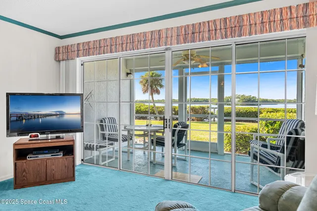a living room with furniture a flat screen tv and floor to ceiling window