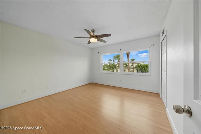 an empty room with windows and ceiling fan