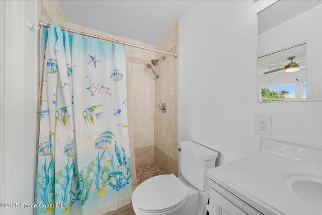 a white toilet sitting next to a bathroom sink and a shower