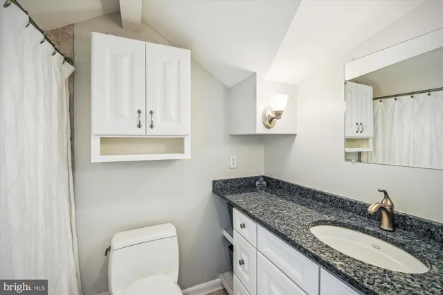 a bathroom with a granite countertop sink a toilet and a mirror
