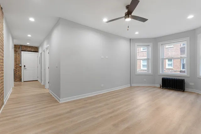 an empty room with windows and a chandelier fan
