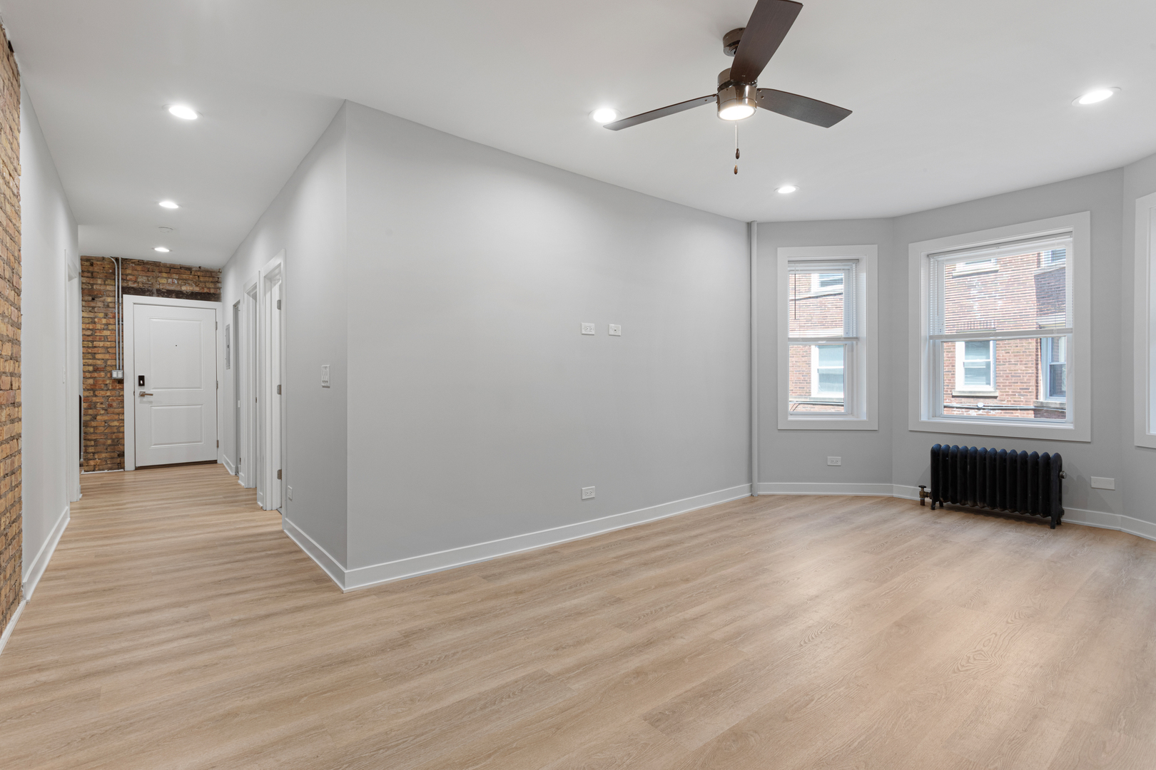 7381 North Damen Avenue, Unit 1E Chicago, IL 60645 - Photo 4 of 13 an empty room with windows and a chandelier fan
