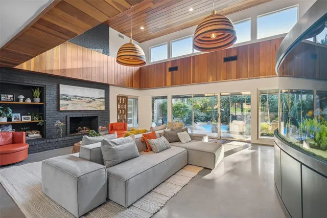 a living room with furniture a fireplace and a floor to ceiling window