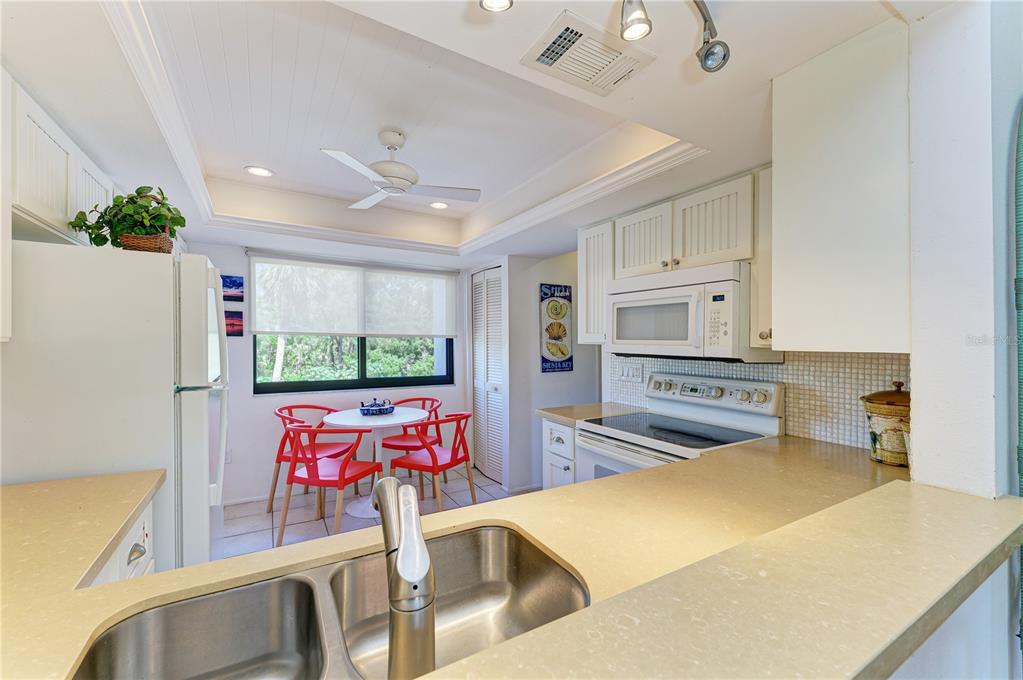 6840 Midnight Pass Road, Unit 6840 Sarasota, FL 34242 - Photo 16 of 66 a kitchen with stainless steel appliances kitchen island granite countertop a refrigerator and a stove top oven