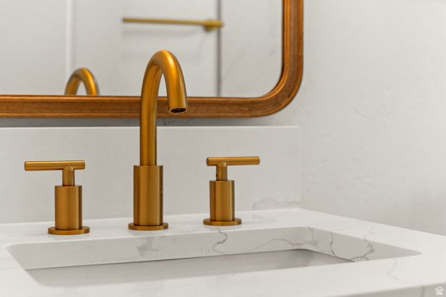 189 West Center Street Midvale, UT 84047 - Photo 24 of 64 Integrated sink with white countertop featuring subtle veining, gold-tone faucet, and coordinating gold-tone mirror frame