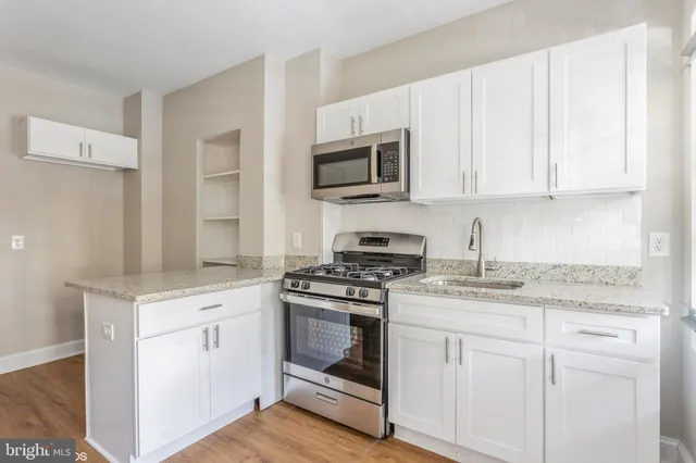 a kitchen with granite countertop white cabinets and stainless steel appliances