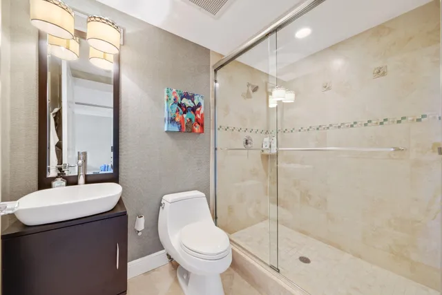 a bathroom with a granite countertop sink a toilet a large mirror a bathtub and shower