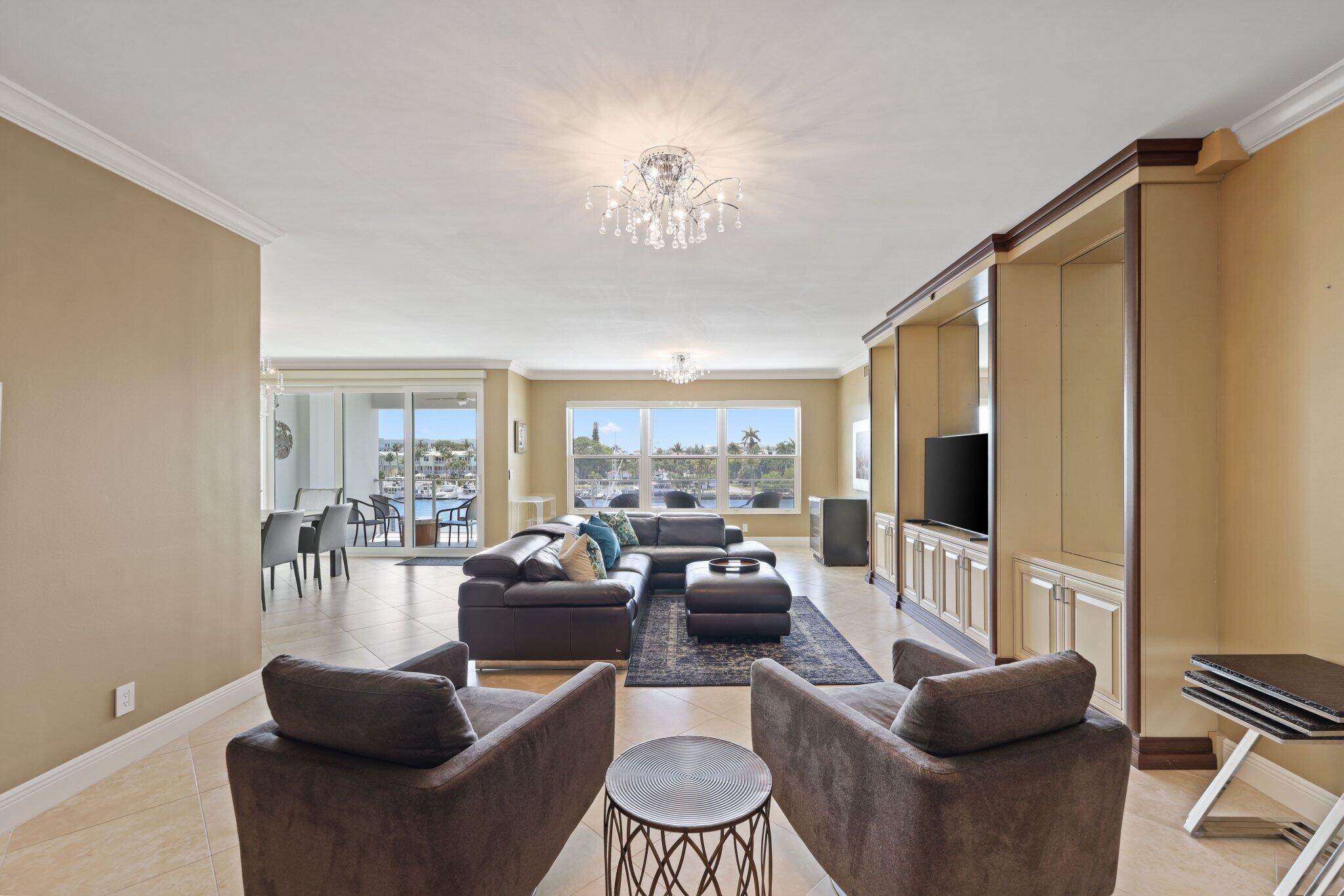 100 Mac Farlane Drive, Unit 3D Delray Beach, FL 33483 - Photo 8 of 57 a living room with furniture a chandelier and a flat screen tv