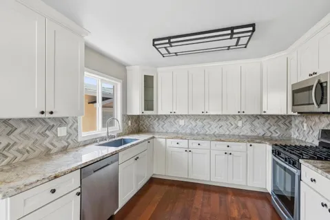 a kitchen with granite countertop a sink a stove and cabinets