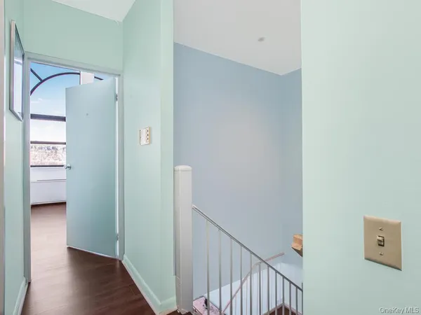 a view of a hallway with wooden floor and a bathroom