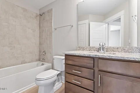 a bathroom with a granite countertop sink toilet mirror and bathtub