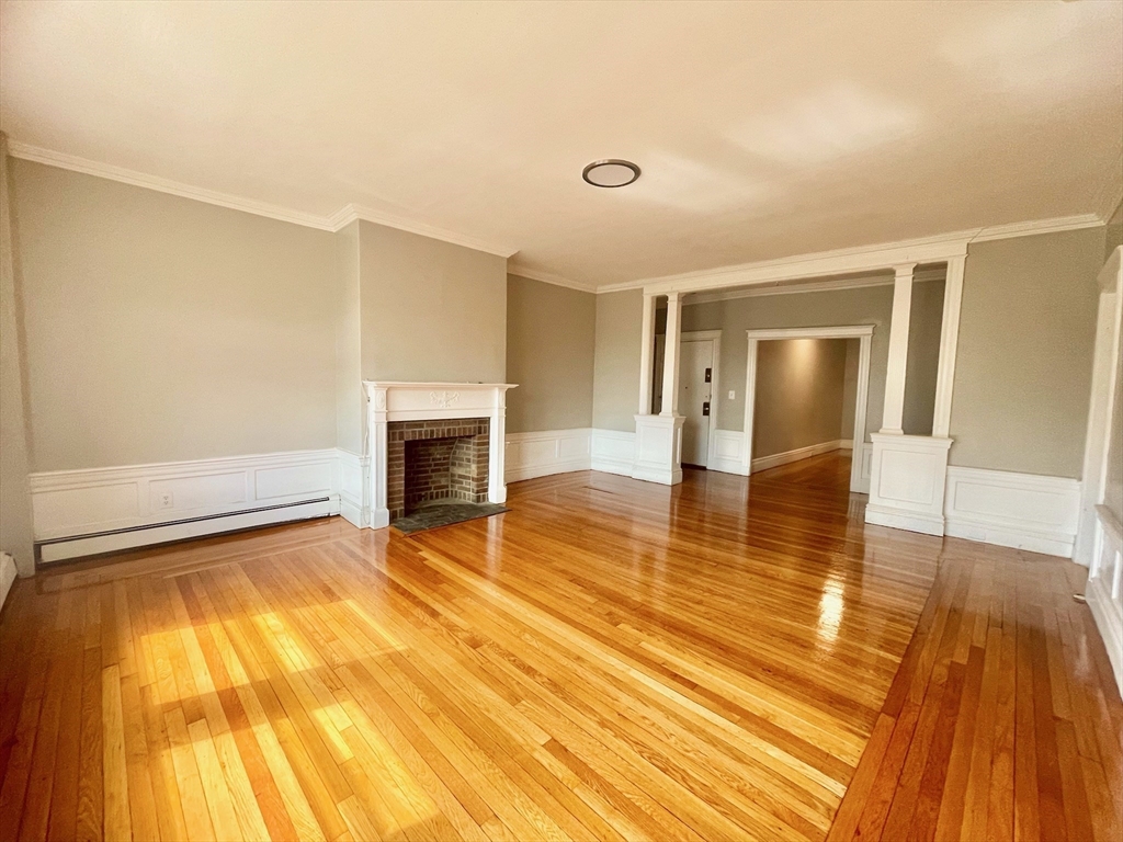 1653 Commonwealth Avenue, Unit 3 Boston, MA 02135 - Photo 4 of 12 a view of empty room with wooden floor and fireplace