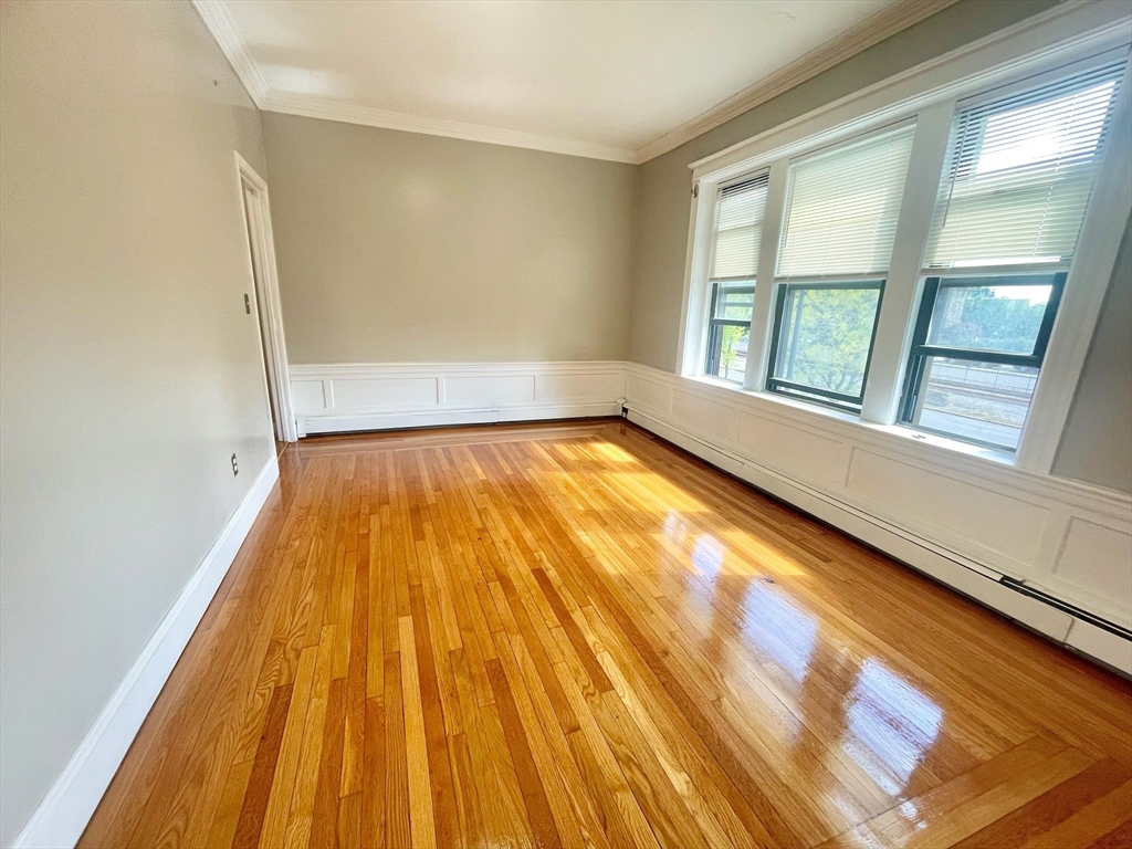 1653 Commonwealth Avenue, Unit 3 Boston, MA 02135 - Photo 5 of 12 a view of an empty room with wooden floor and a window