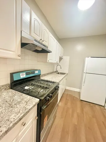 a kitchen with stainless steel appliances granite countertop a stove a refrigerator and a white cabinets