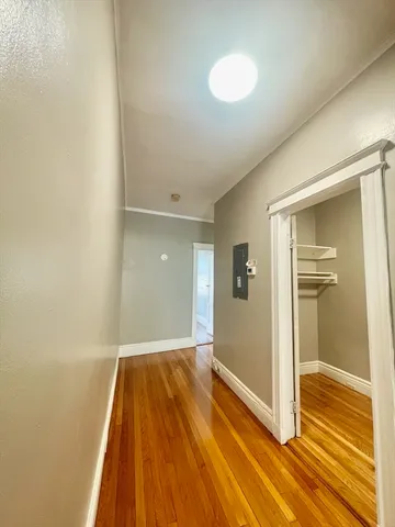 a view of a hallway with wooden floor and closet