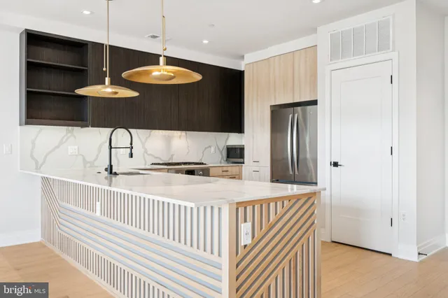 a room with stainless steel appliances a chandelier and a refrigerator