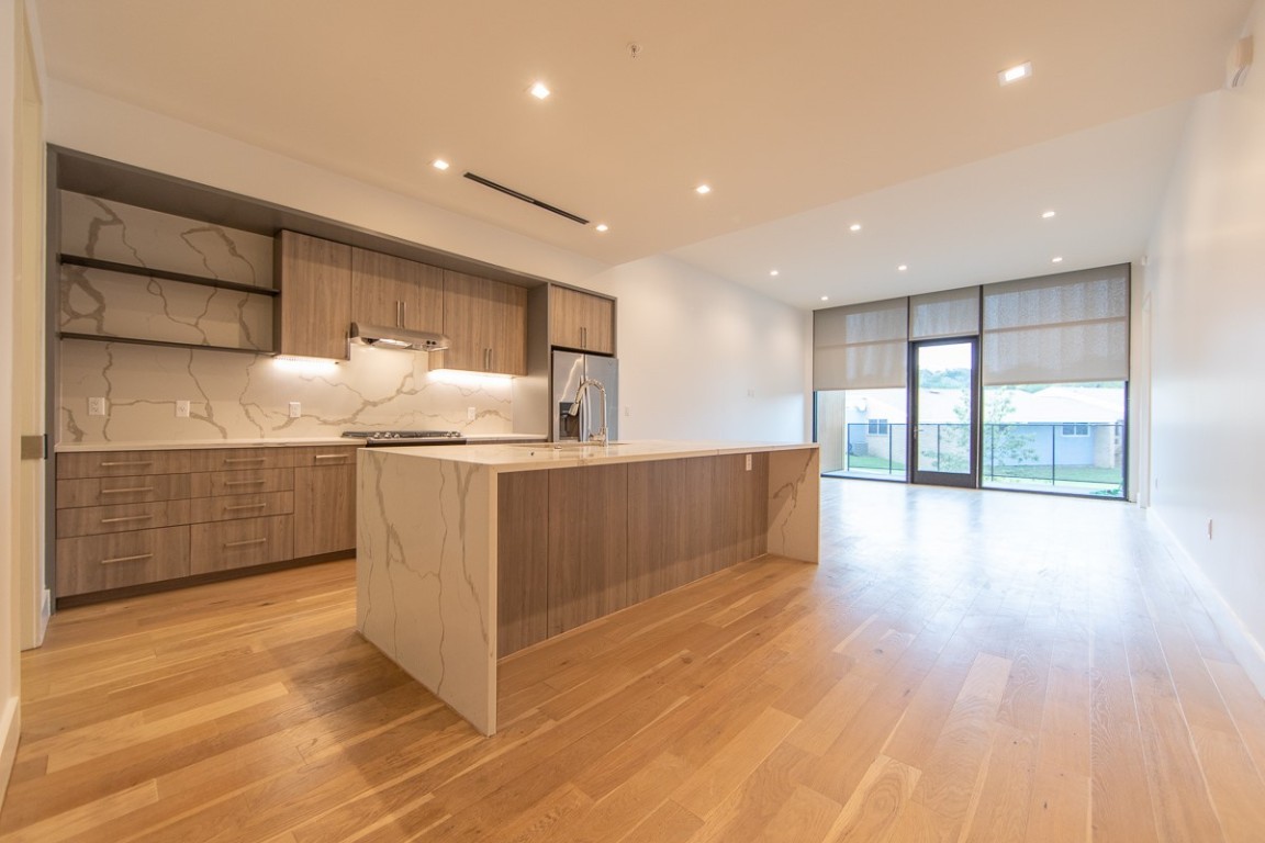 a kitchen with stainless steel appliances kitchen island wooden floors wooden cabinets and entryway