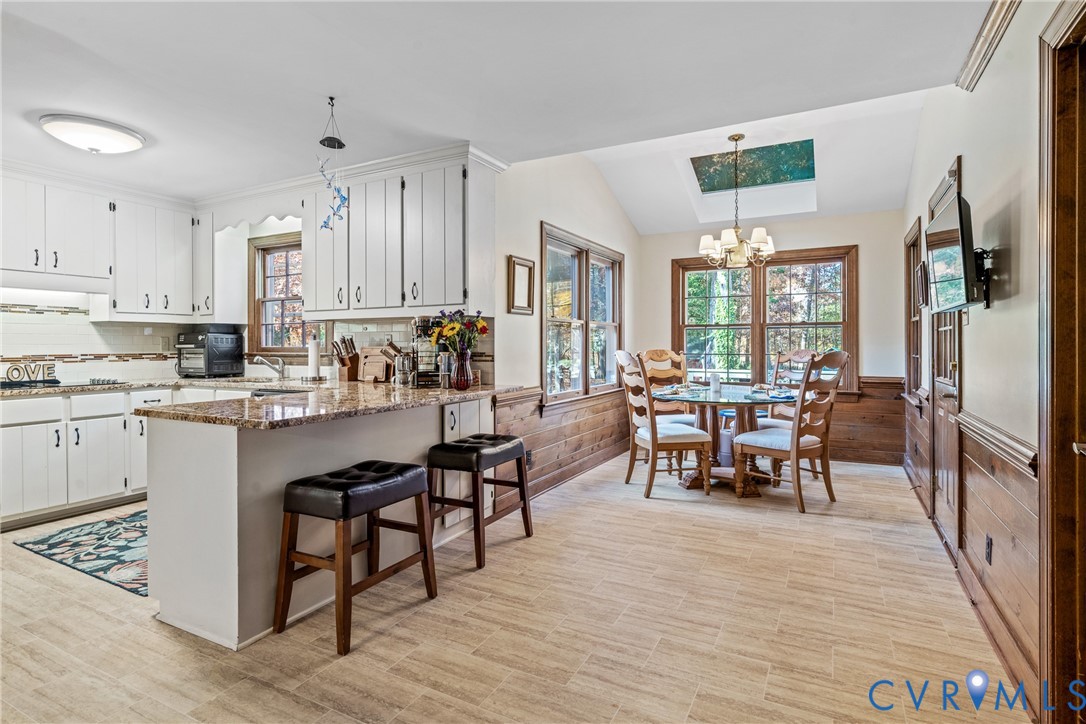 8404 Copperpenny Terrace Chesterfield, VA 23832 - Photo 12 of 40 a kitchen with stainless steel appliances kitchen island granite countertop a stove a refrigerator a sink a dining table and chairs with wooden floor