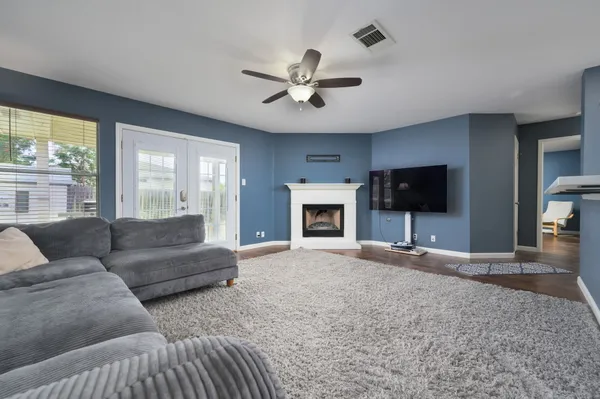 a living room with furniture a ceiling fan and a flat screen tv