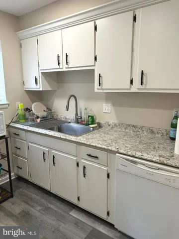 a kitchen with granite countertop white cabinets and a sink