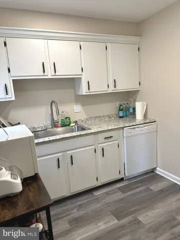 a kitchen with granite countertop a sink cabinets and wooden floor
