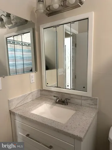 a bathroom with a granite countertop sink and mirror with window