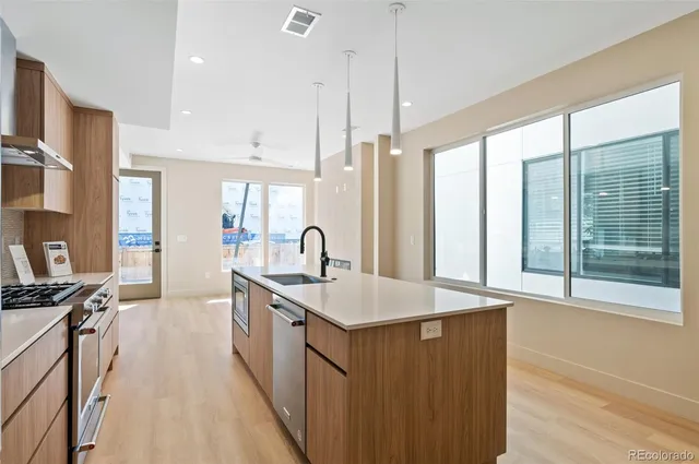 a large kitchen with kitchen island a large counter top a sink a stove and a window