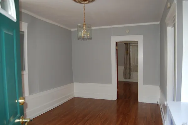a view of a hallway with wooden floor and chandelier