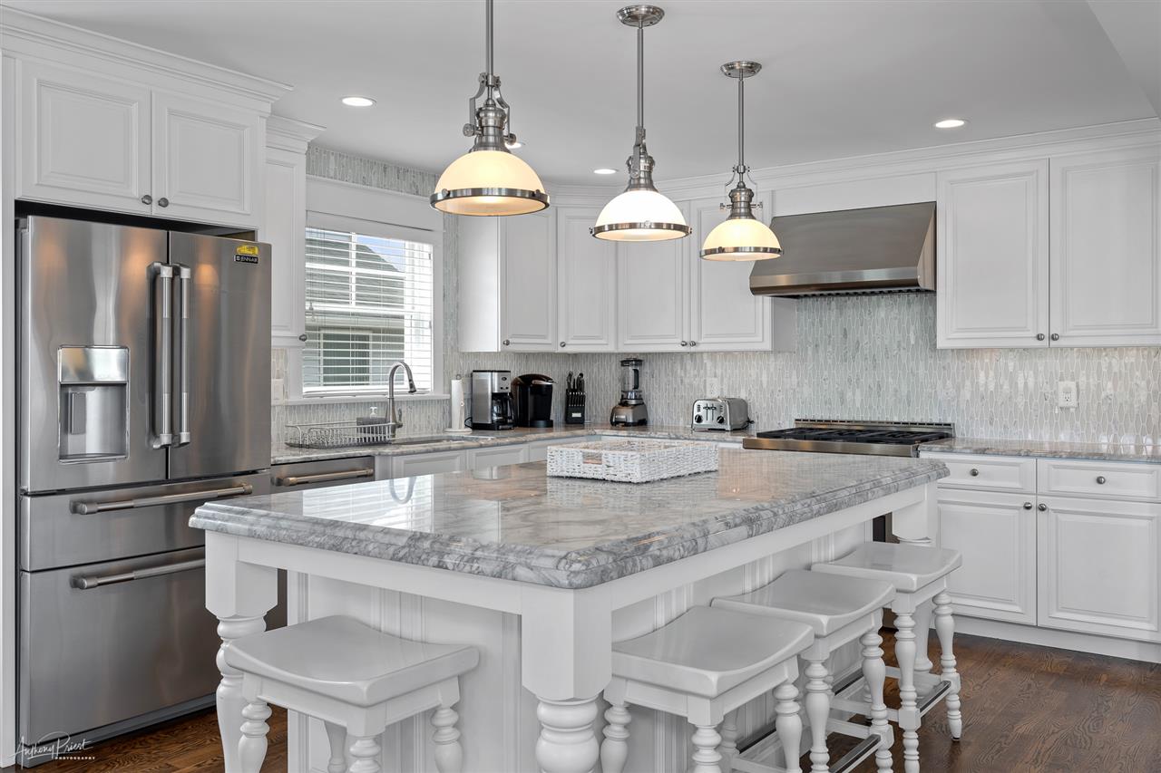 45 West 26th Avalon, NJ 08202 - Photo 5 of 24 a kitchen with stainless steel appliances granite countertop a sink a stove a refrigerator cabinets and chairs