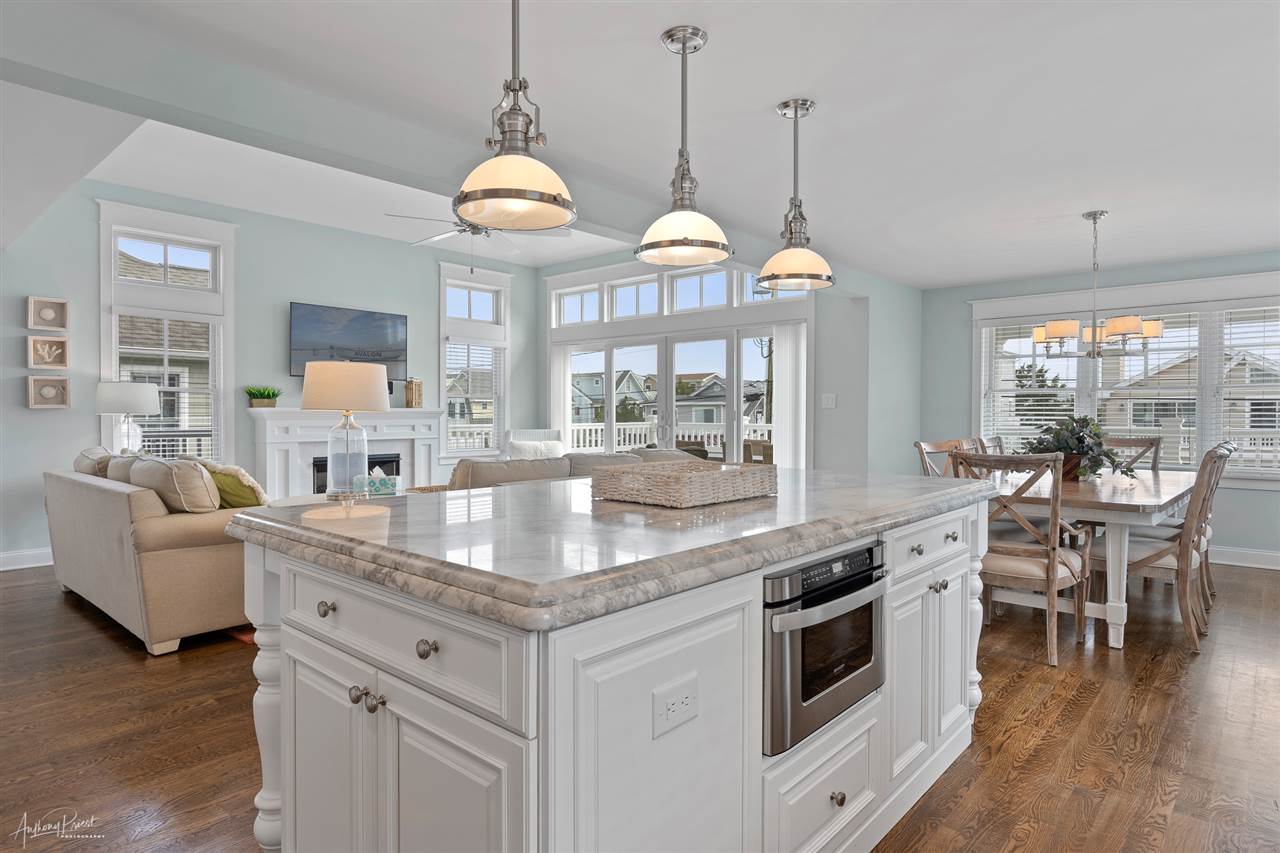 45 West 26th Avalon, NJ 08202 - Photo 7 of 24 a kitchen with stainless steel appliances granite countertop a stove a oven a dining table and chairs with wooden floor