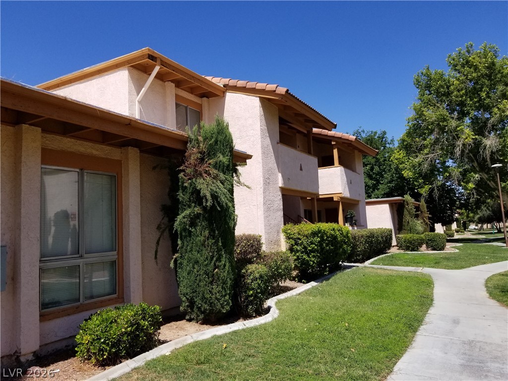 1515 East Reno Avenue, Unit A103 Las Vegas, NV 89119 - Photo 1 of 16 This residential building features traditional stucco siding and a classic tiled roof, nestled among verdant landscaping with well-maintained grassy areas and a paved pathway.