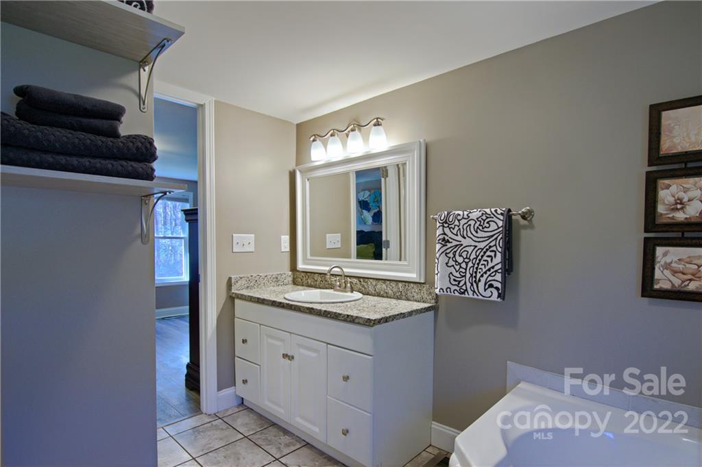 20 Cascade Village Road, Unit 2 Pisgah Forest, NC 28768 - Photo 21 of 36 a bathroom with a granite countertop sink and a mirror